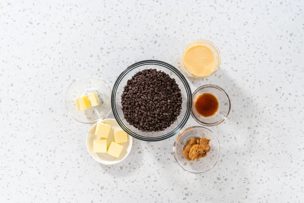 Düz yatıyordu. Fıstık ezmeli çikolata yapmak için cam karıştırma kabında ölçülmüş malzemeler..