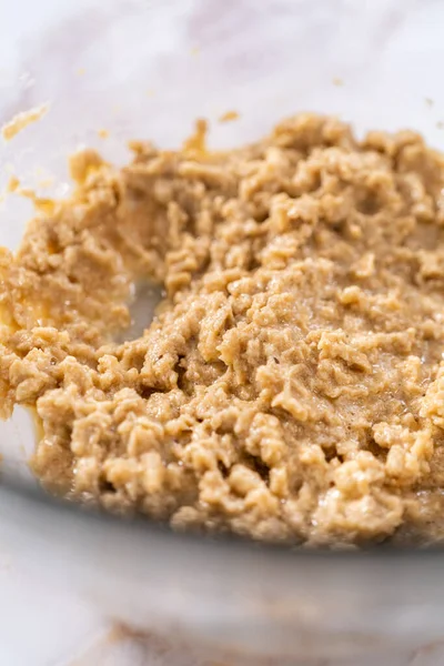 Elmalı yulaflı kurabiye pişirmek için büyük bir bardakta karıştırma malzemesi..