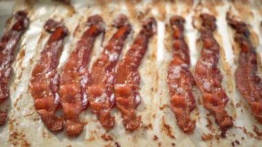 Time lapse. Step by step. Cooked bacon strips on a white tray with a paper towel.