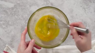 Time lapse. Flat lay. Step by step. Mixing ingredients in a glass mixing bowl to prepare chocolate mug cakes.