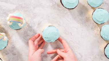 Düz yatıyordu. Adım adım. Çikolatalı kekleri tereyağlı krema ve gökkuşağı şekeriyle süslüyorum..