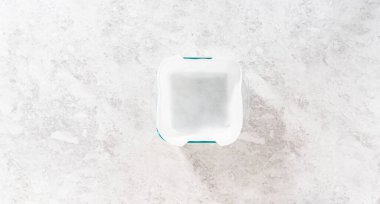 Düz yatıyordu. Şekerli mısır şekeri hazırlamak için kare peynirli kek tavasını kağıt kağıtla kaplamak.