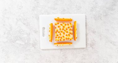 Düz yatıyordu. Beyaz bir kesme tahtasının üzerinde şekerli mısır şekerini kare parçalara ayırmak..