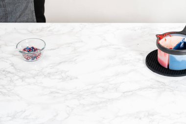 Flat lay. Dipping pretzels twists into melted chocolate to make red, white, and blue chocolate-covered pretzel twists.