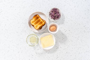 Düz yatıyordu. Kahvaltı yumurtası ve filizli sandviç yapmak için cam karıştırma kabında ölçülmüş malzemeler..