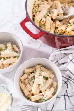 Küçük bir kasede yeşil bezelyeli tavuk ve rigatoni makarna..