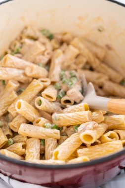 Alfredo soslu tavuk pişirmek için mayalı bir fırının içindekileri karıştırıyorum..