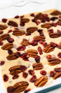 Beyaz çikolatalı fındıklı fındıklı çikolatalı şekerlemeyi hazırlamak için parşömen kağıdıyla kaplanmış fırın tavasına şekerleme döküyorum..