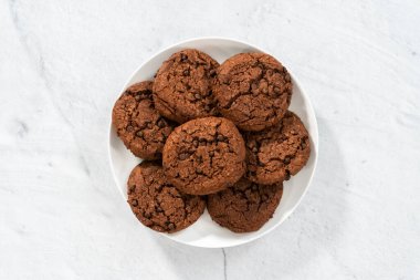 Düz yatıyordu. Taze pişmiş çifte çikolatalı kurabiyeler beyaz tabakta..