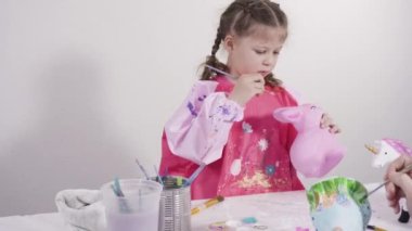 Küçük kız evde eğitim projesi için akrilik boyayla heykelcikler boyuyor..