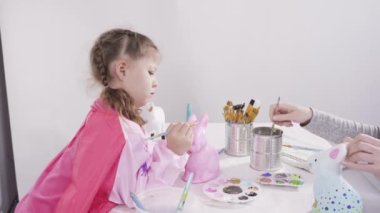 Küçük kız evde eğitim projesi için akrilik boyayla heykelcikler boyuyor..