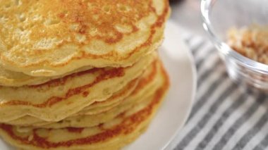 Dilimlenmiş muz, kızarmış hindistan cevizi ve akçaağaç şurubuyla süslenmiş taze hindistan cevizli krep yığını..