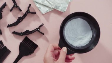 Siyah plastik bir kasede pembe arka planda saç boyası tozu..