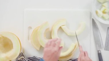 Time lapse. Flat lay. Slicong golden dewlicious melon on a white cutting board.