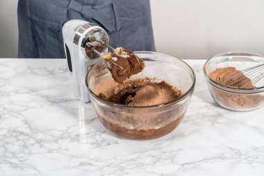 Mixing ingredients with a hand mixer to bake chocolate cookies with chocolate hearts for Valentines Day.