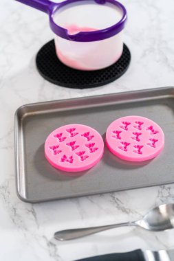 Panda şeklindeki kurabiyeleri süslemek için pembe çikolata yayları hazırlıyorum..