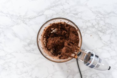 Flat lay. Mixing ingredients with a hand mixer to bake chocolate cookies with chocolate hearts for Valentines Day.
