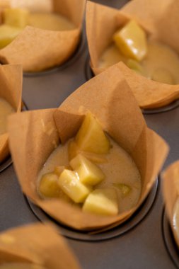 Sharlotka çörekleri pişirmek için parşömen kağıtlarıyla kaplanmış kek tavasına hamur atıyorlar..