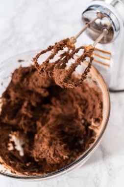 Mixing ingredients with a hand mixer to bake chocolate cookies with chocolate hearts for Valentines Day.