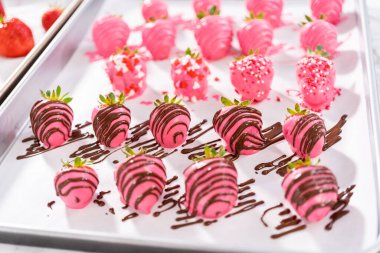 Çikolata kaplı çilekleri çikolata parçacıkları ve çikolata parçacıklarıyla süslemek..