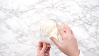 Time lapse. Flat lay. Step by step. Mixing ingredients for mini pancake cereal in a glass mixing bowl.