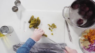 Düz yatıyordu. Adım adım. Sirkeli salata için beyaz bir kesme tahtasındaki sebzeleri dilimliyorum..