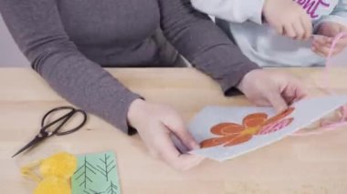 Zaman aşımı. Küçük kız annesiyle el sanatları masasında dikiş dikmeyi öğreniyor..