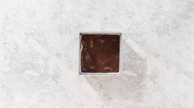 Düz yatıyordu. Çubuk şekerleme hazırlamak için kareli peynirli kek kalıbını parşömen kağıdıyla dolduruyorum..