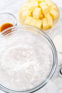 Amerikan bayrağı mini kekleri için tereyağlı krema yapmak için cam karıştırma kaselerinde ölçülmüş malzemeler..