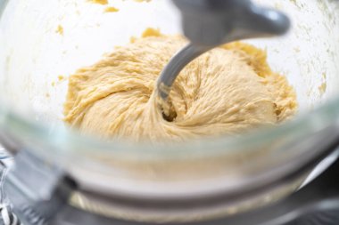 Ev yapımı brioche çörekleri pişirmek için mutfak mikserindeki malzemeleri karıştırıyorum..