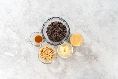 Düz yatıyordu. Çikolatalı macadamia şekerlemesi yapmak için cam karıştırma kabında ölçülmüş malzemeler..