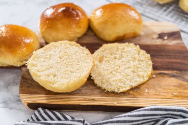 Odun kesme tahtasının üzerinde taze pişmiş çörekleri dilimliyorum..