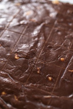 Küçük kare parçaları kesmek için tekerlek hamuru kesicisi kullanarak çikolatalı macadamia şekerlemesi yapmak.