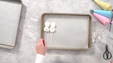 Time lapse. Flat lay. Step by step. Piping meringue mix into unicorn-shaped pops on a baking sheet lined with parchment paper.