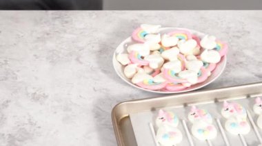 Adım adım. Taze pişmiş tek boynuzlu at kurabiyelerini fırından alıp beyaz servis tabağına koyuyorlar..