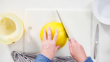 Adım adım. Düz yatıyordu. Beyaz kesme tahtasında kaygan altın çiğ taneli kavun.