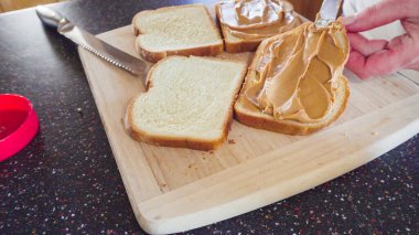 Preparing peanut butter and jelly sandwich on a wood cutting board. clipart