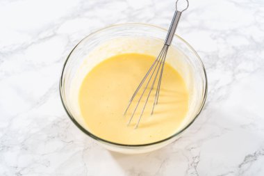 Büyük bir bardakta ıslak malzemeler karıştırarak kırmızı kadife kekler ve beyaz çikolatalı ganache kreması pişiriyorum..