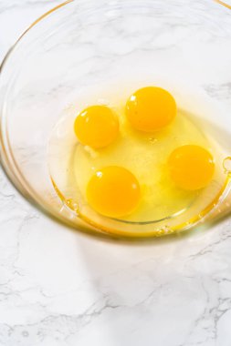 Büyük bir bardakta ıslak malzemeler karıştırarak kırmızı kadife kekler ve beyaz çikolatalı ganache kreması pişiriyorum..