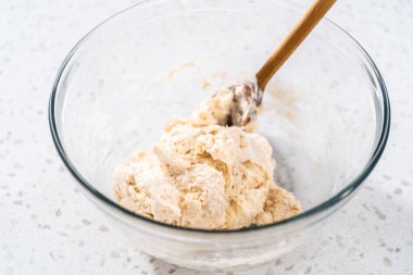 Büyük bir cam kasede ahşap bir kaşıkla karıştırılan malzemeler naan dippers pişirir..