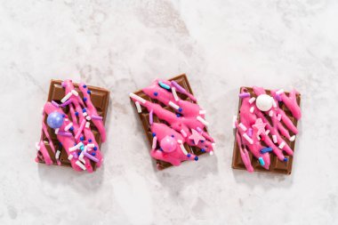 Üzerine pembe çikolata serpiştirilmiş gurme mini çikolatalar ve süslü şekerler serpiştirilmiş..