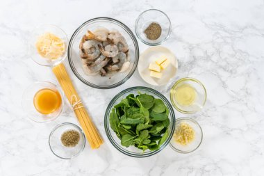 Sarımsaklı karides makarnasını ıspanakla hazırlamak için cam karışımında ölçülmüş malzemeler..