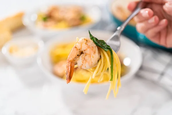 Serving garlic shrimp pasta with spinach in white ceramic bowls.