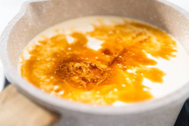 Beyaz çikolatalı ganache kreması yapmak için tencerede krem şanti ısıtılıyor..