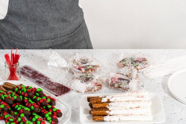 Denver, Colorado, USA-December 18, 2022-Packaging homemade chocolate-covered pretzels into clear plastic bags for Christmas gifts.