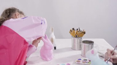 Küçük kız evde eğitim projesi için akrilik boyayla heykelcikler boyuyor..