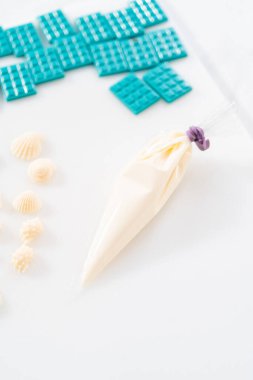 Çiseleyen beyaz çikolata ve üzerine beyaz inci şekeri serpiştiren mini çikolata ozanı.