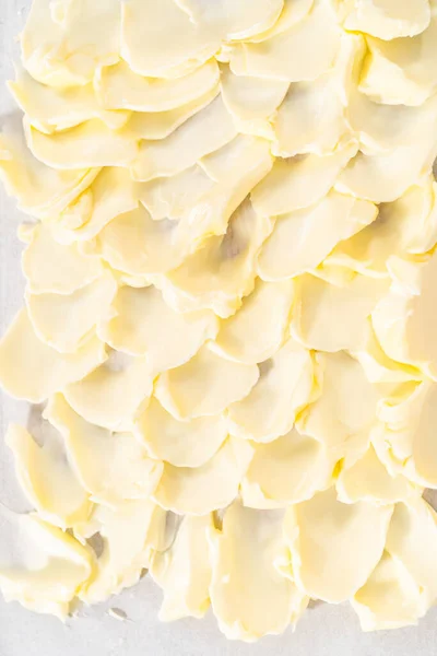 Spreading unsalted butter at room temperature to prepare a vegetarian party butter board for a party.
