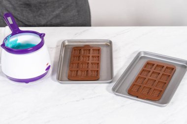 Çikolata kalıplarını erimiş çikolatayla doldurarak küçük denizkızı çikolatalarını hazırlıyorum..