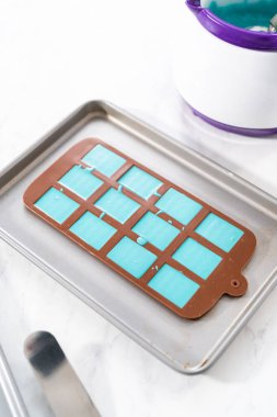 Çikolata kalıplarını erimiş çikolatayla doldurarak küçük denizkızı çikolatalarını hazırlıyorum..